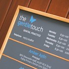 A detail from the door sign at The Gentle Touch, showing the logo and opening times