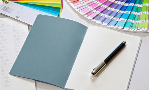 A blank notebook page surrounded with Pantone and coloured paper swatches