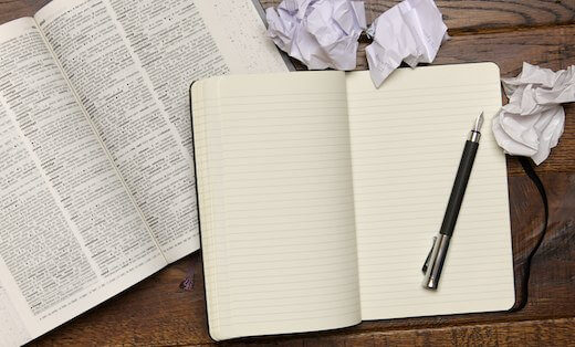 A blank page of a notebook, with a dictionary and pen