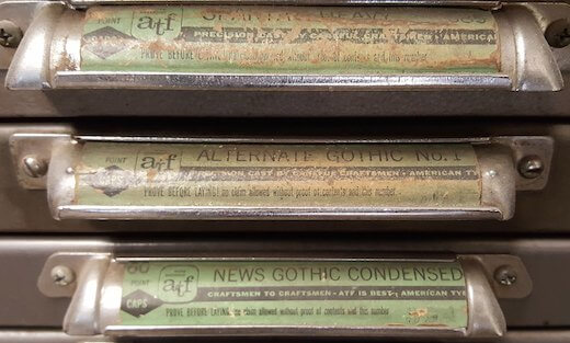 Name labels on the drawer handles of a letterpress type cabinet