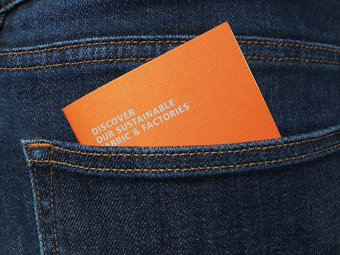 A small orange booklet peeks out of the pocket of a pair of demin jeans
